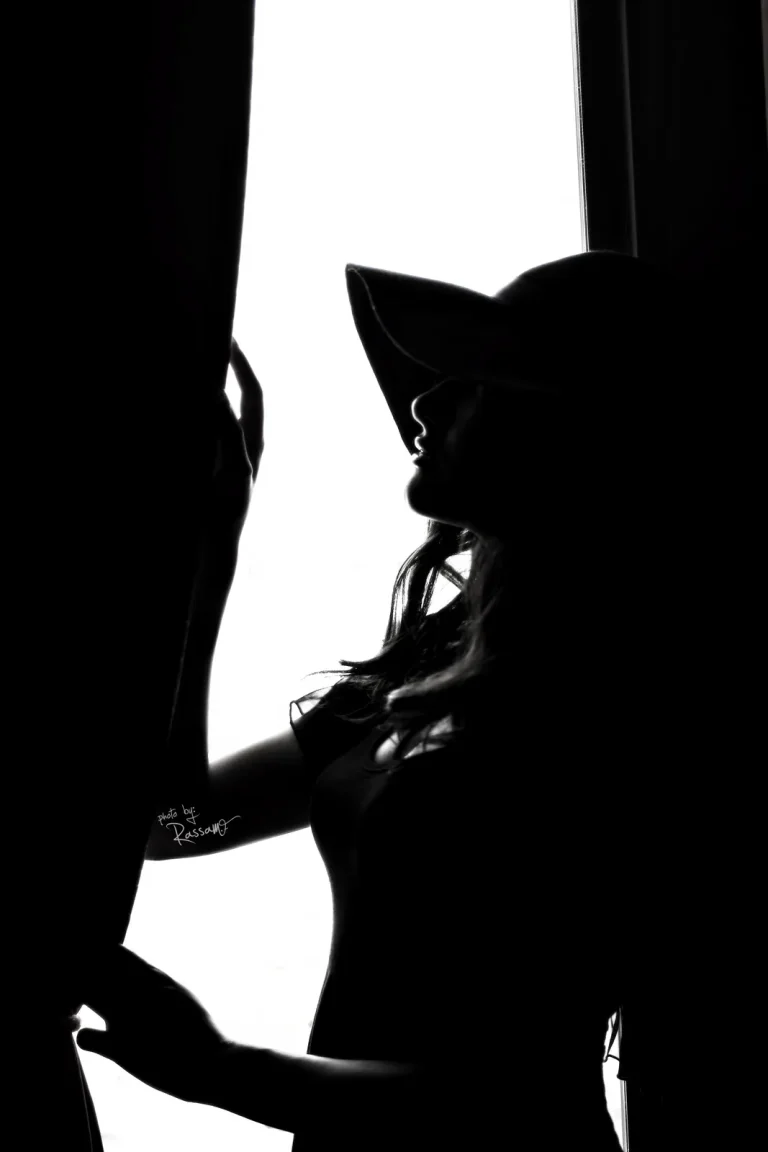 Silhouette of a woman in a wide-brimmed hat against a bright window