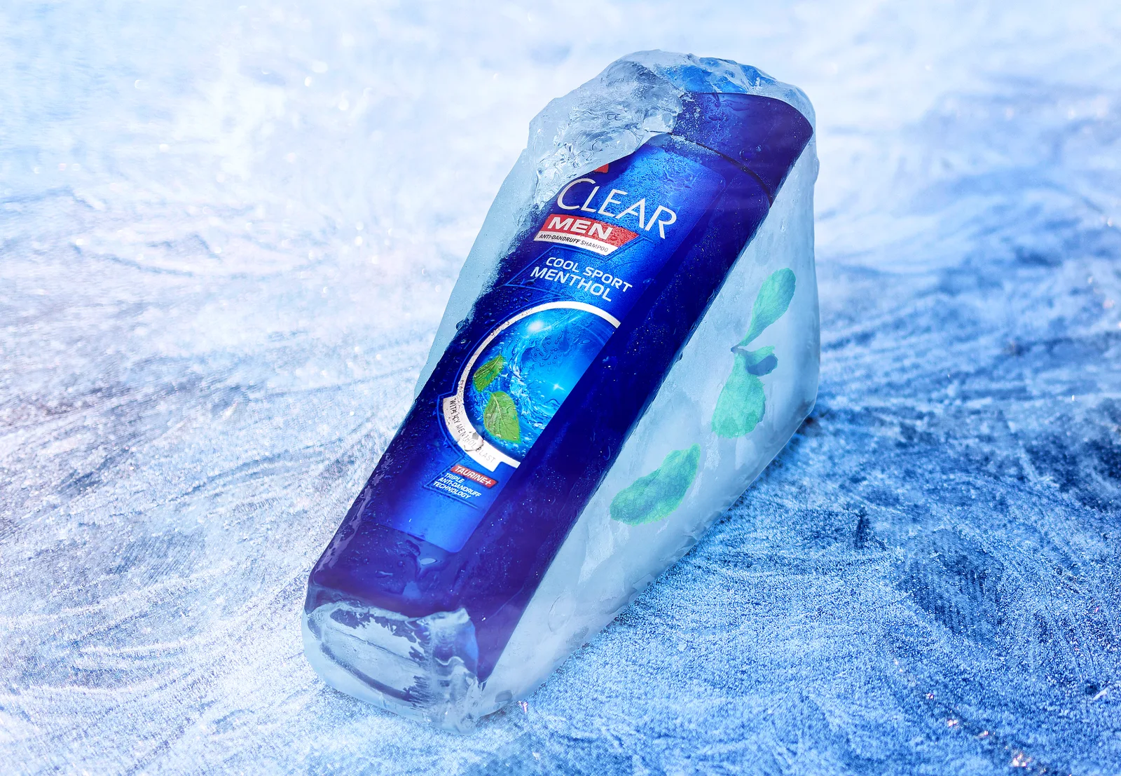 Blue Clear Men Cool Sport Menthol shampoo bottle frozen in an ice block with mint leaves, on frost.