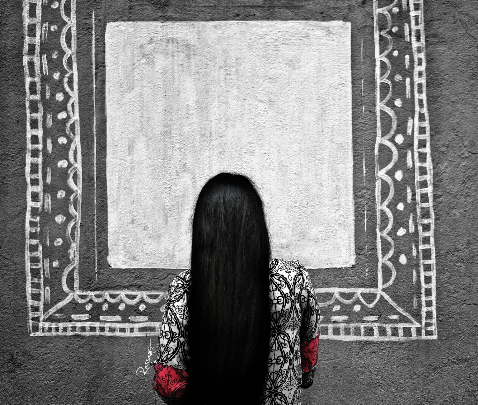 A woman facing a blank painted frame on a wall