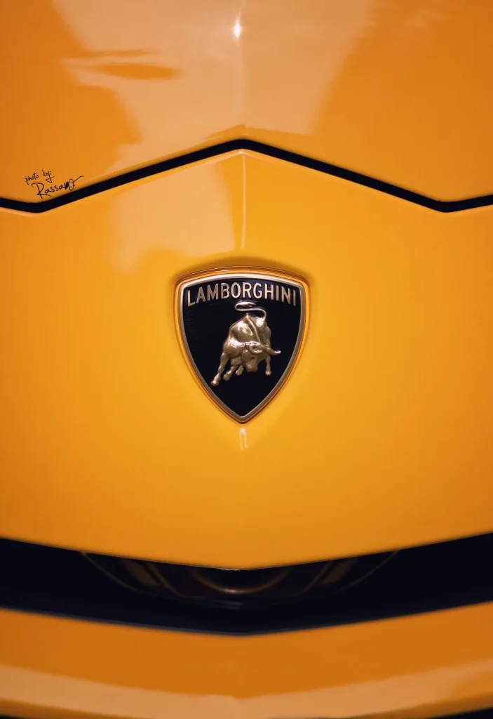 Symmetrical close-up of a glossy yellow Lamborghini nose with the black and gold bull shield at centre.