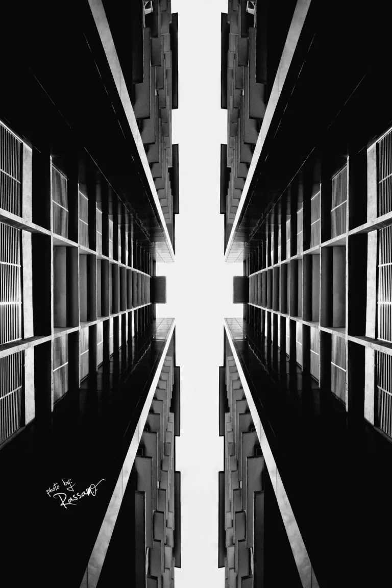 Two towers mirrored around a narrow strip of sky, looking straight up