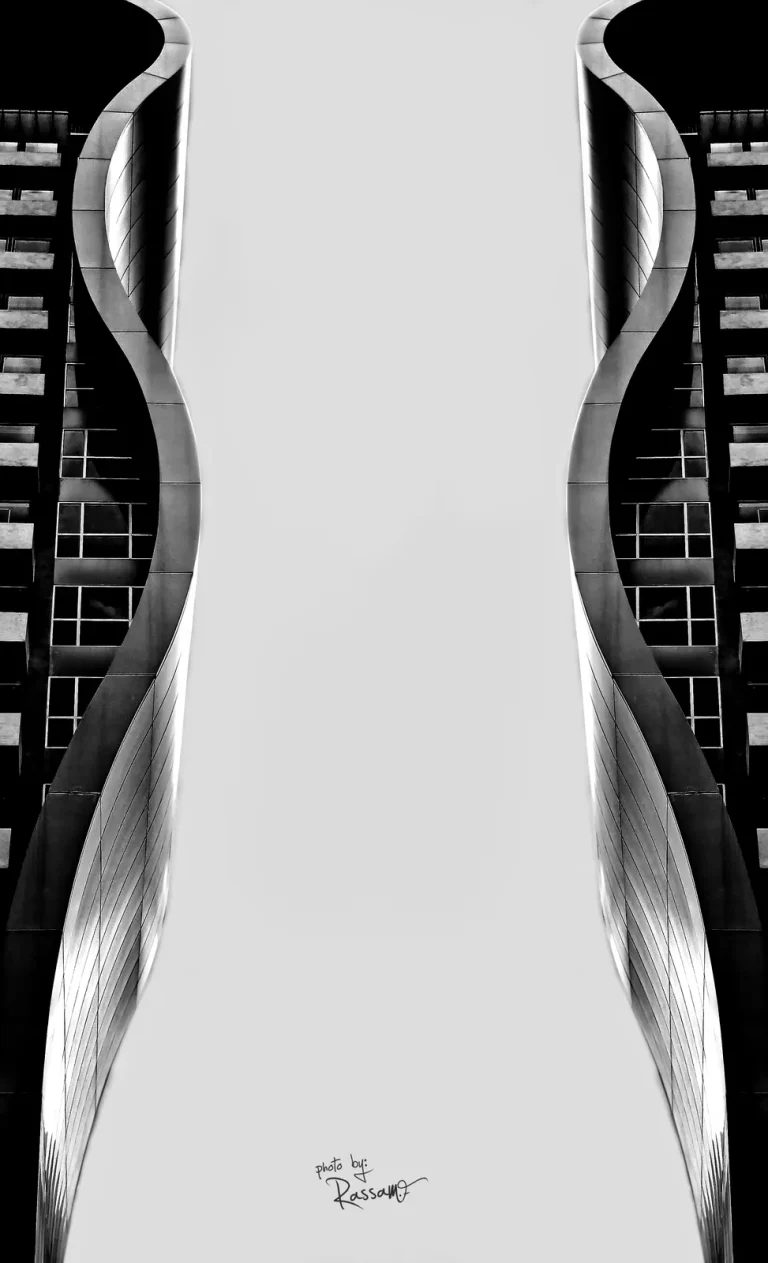 Two curved towers framing a white sky, looking straight up