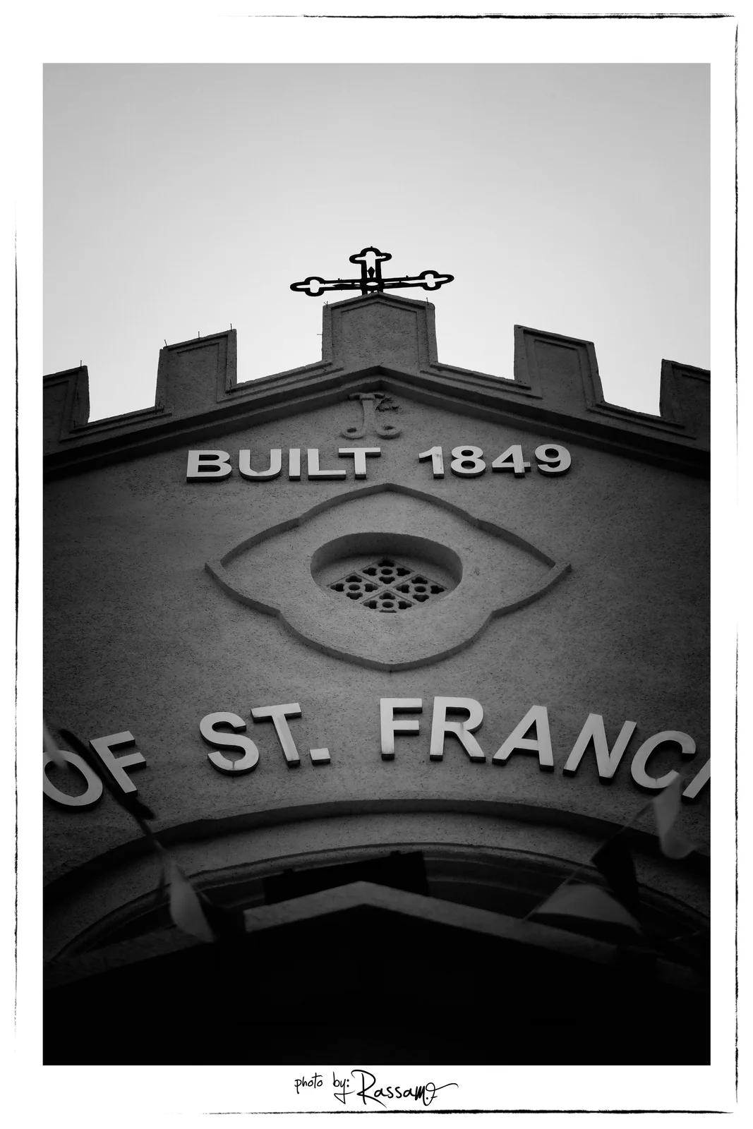 The words Built 1849 and part of the church name over the entrance, seen from below, black and white