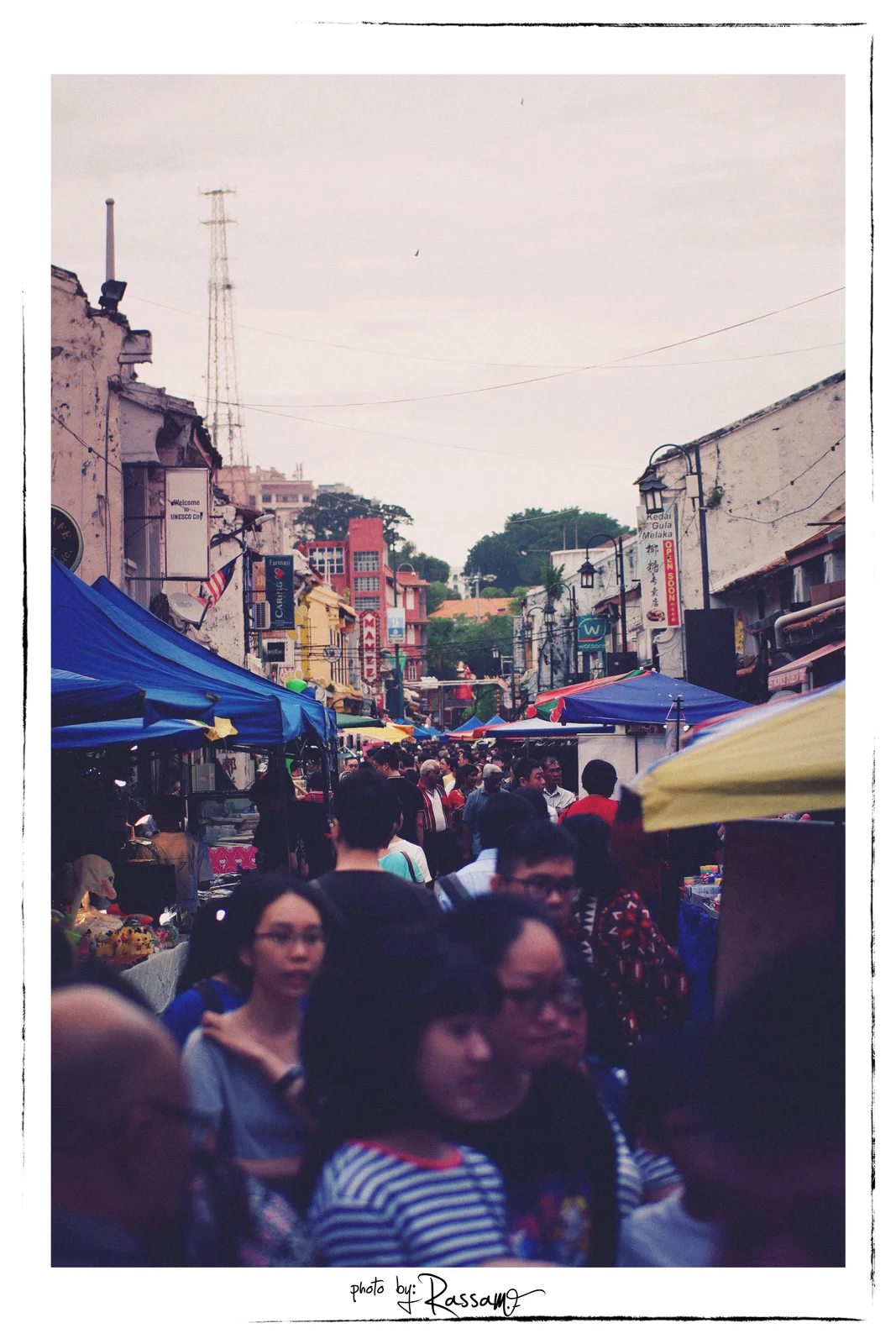 A crowded market street at Jonker Walk with blue tents, shop signs and faces in the foreground