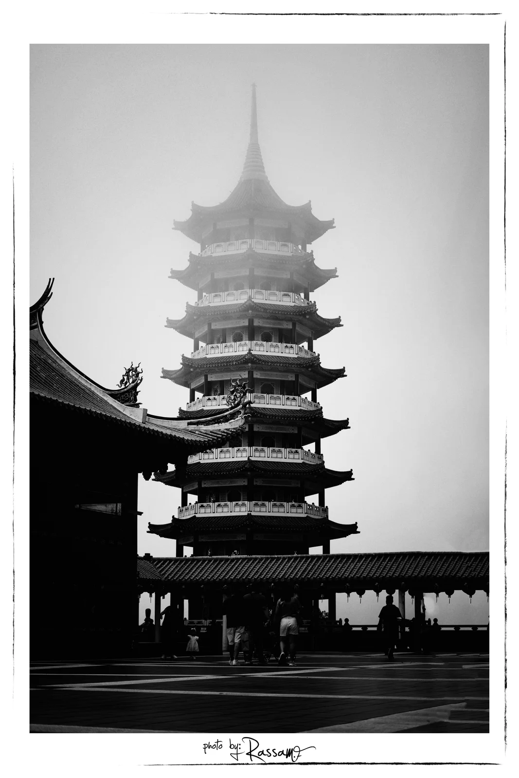 The temple pagoda fading into mist above a courtyard with small figures, black and white